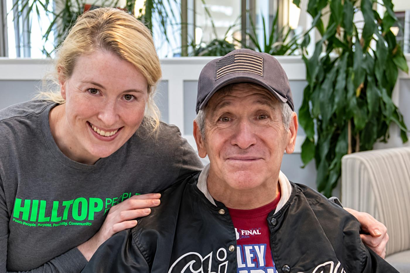 Hilltop Brain Injury Services staff member and resident smiling together on campus.